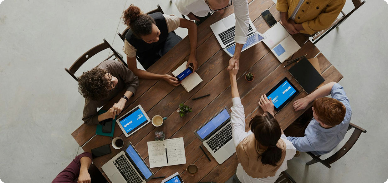 a group of people around a table with laptops